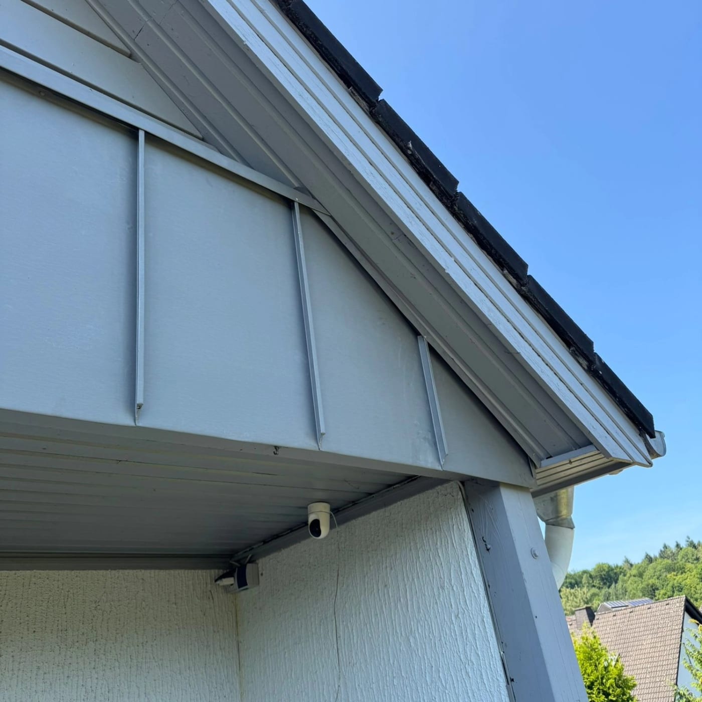 Stehfalzverkleidung aus Metall an einer Hausfassade unter dem Dachüberstand