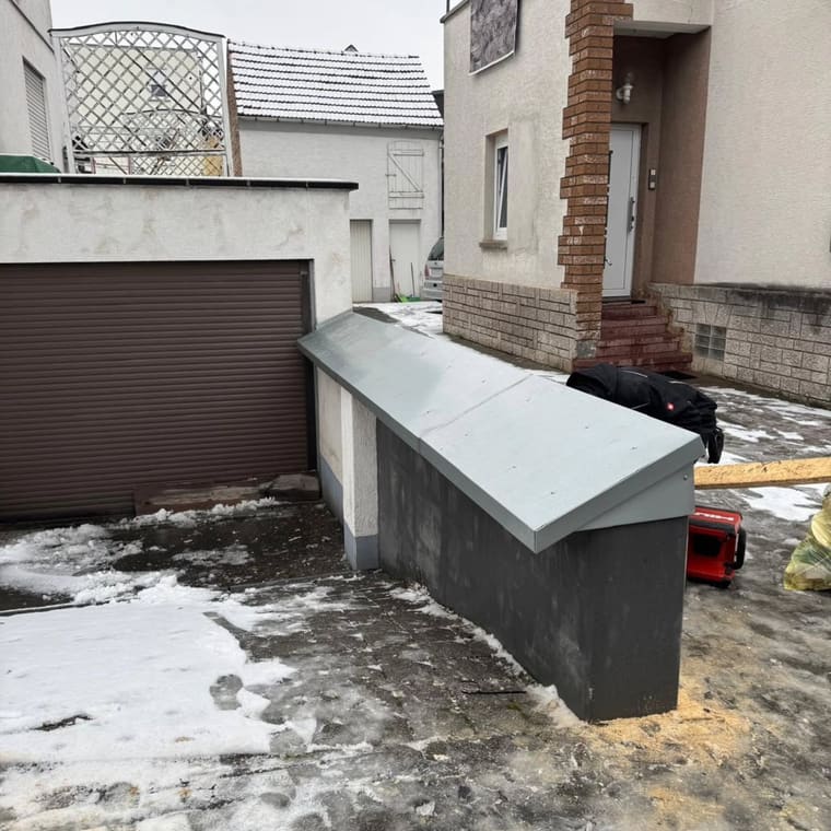Neue Mauerabdeckung aus Blech auf einer Gartenmauer im Winter